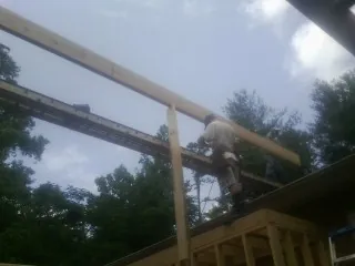 Carpenter setting a ridge beam over a new addition frame — Ice Dam Removal by Roofing Brothers in Upper Falls