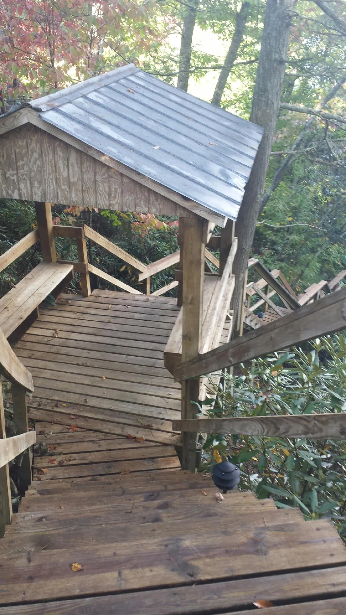 Metal roofed shelter over wooden steps on a wooded walkway — Skylight Repair & Installation work by our crew in Upper Falls