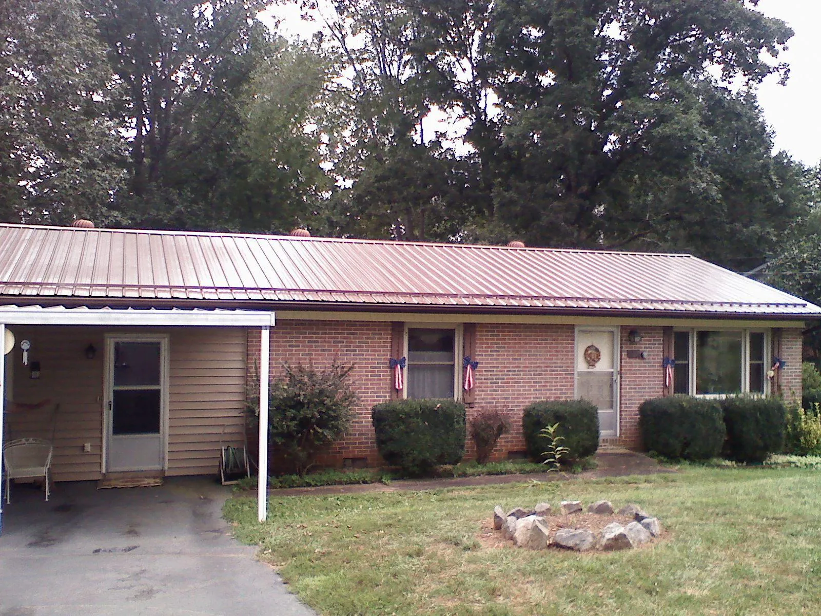 Bronze metal roof and carport on a brick ranch home — Roof Repair work by our crew in Upper Falls